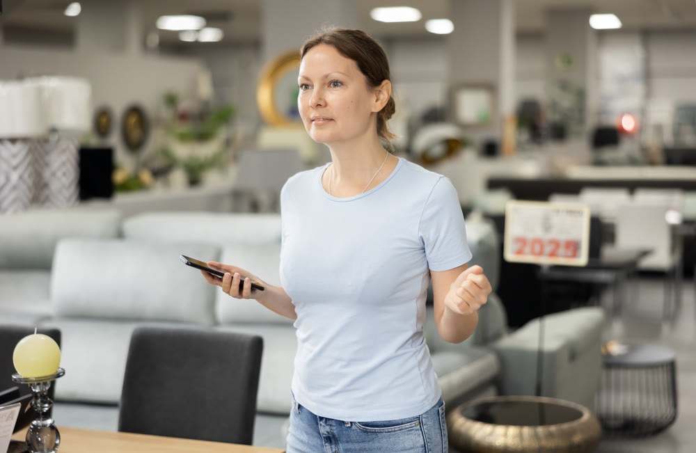 Portrait of woman consulted on phone while looking for new furniture in salon