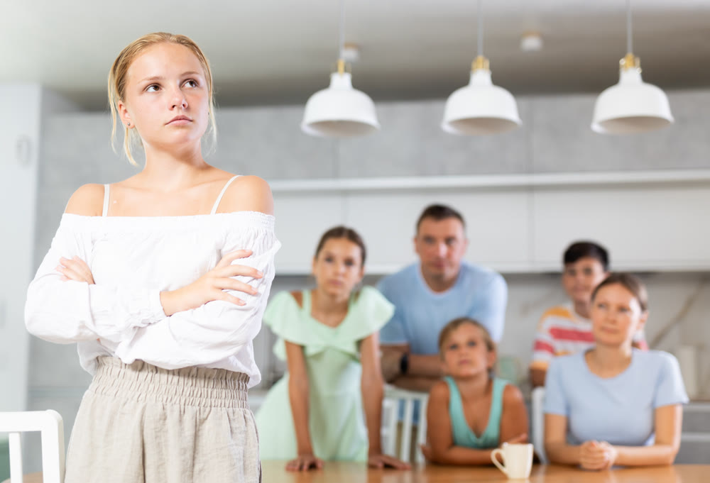 Angry female child turned away from parents and sisters and ignores relatives.