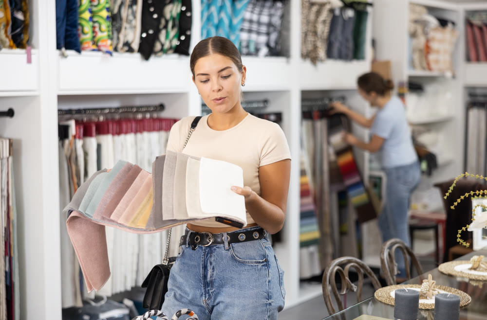 Positive young girl choosing fabric upholstery in furniture salon