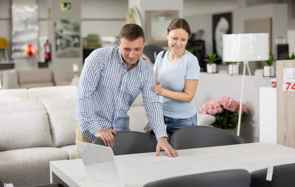 Spouses choose dining table desk in furniture store showroom