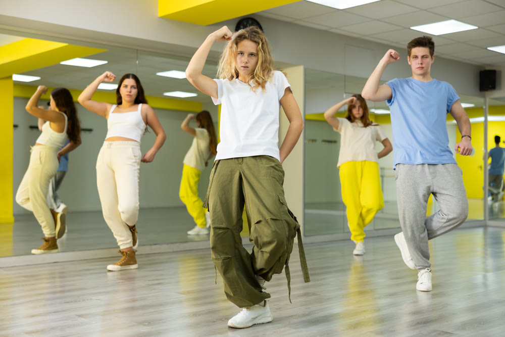 Teenagers dancing hip-hop in studio, learn dance moves together, wearing stylish outfit