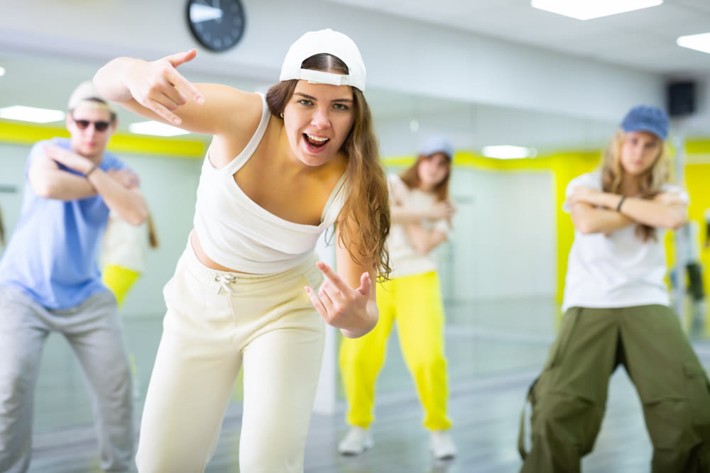 Young girl in cap training breakdance Toprock moves in dance hall