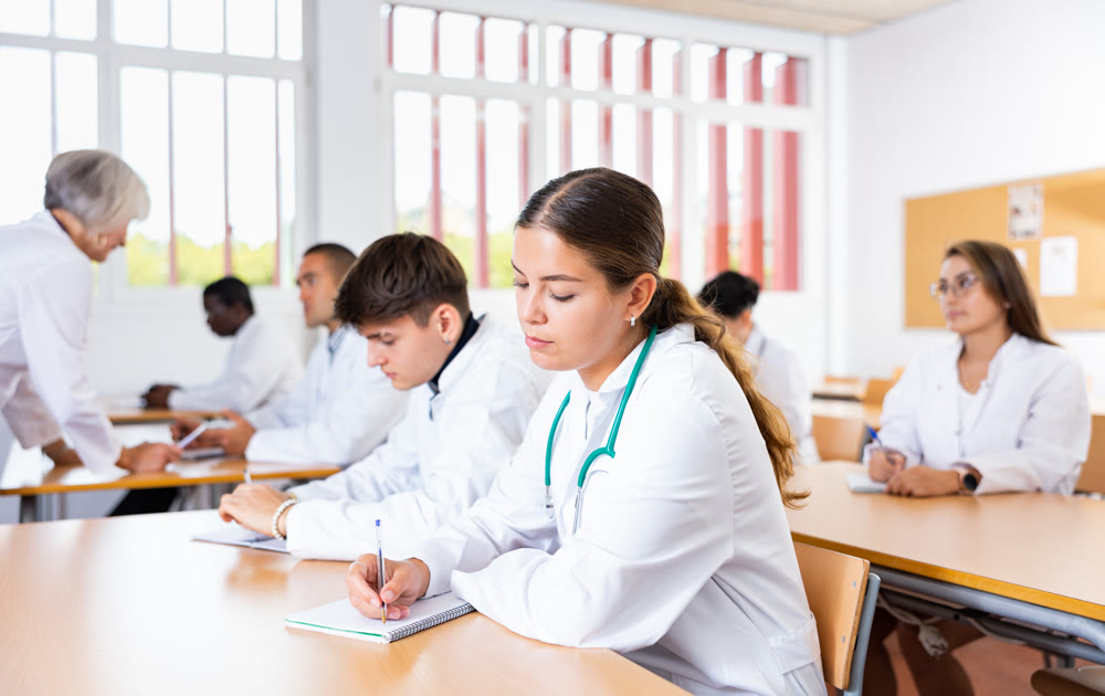 Doctors different age sitting at desk in classroom working during lesson at education class