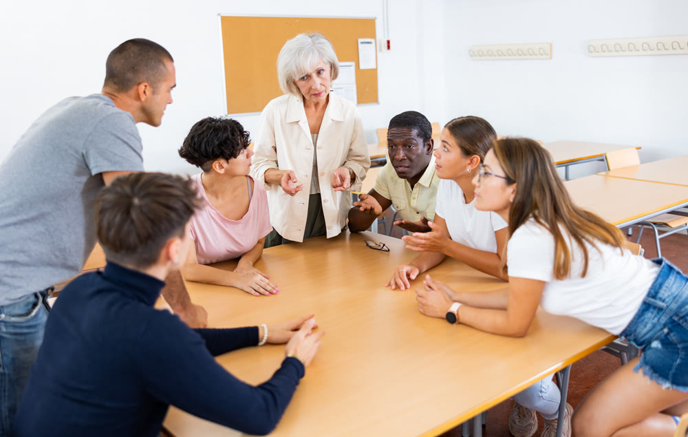 Group of people communicating in Spanish-speaking club with elderly female tutor