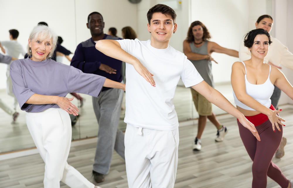 Smiling guy learning dynamic dances in group choreography class