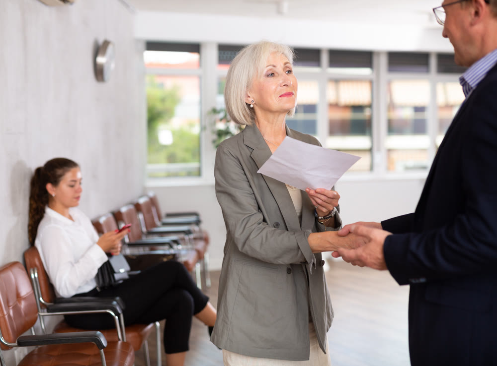 Old woman handshaking with other person in waiting room