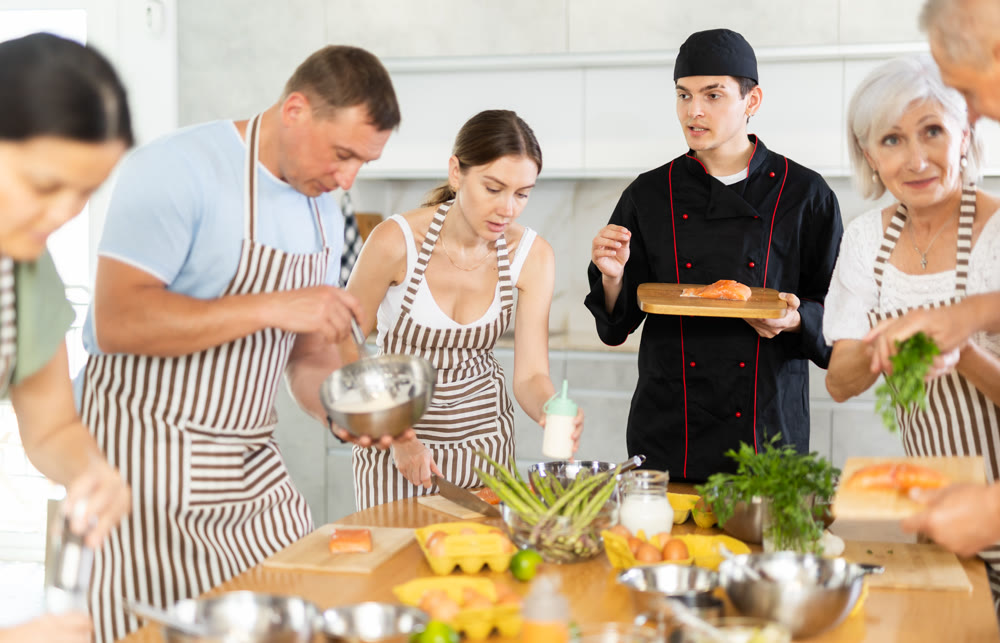 Young chef sharing secrets of cooking salmon at culinary class