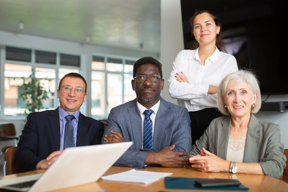 Group of different people posing at table in office