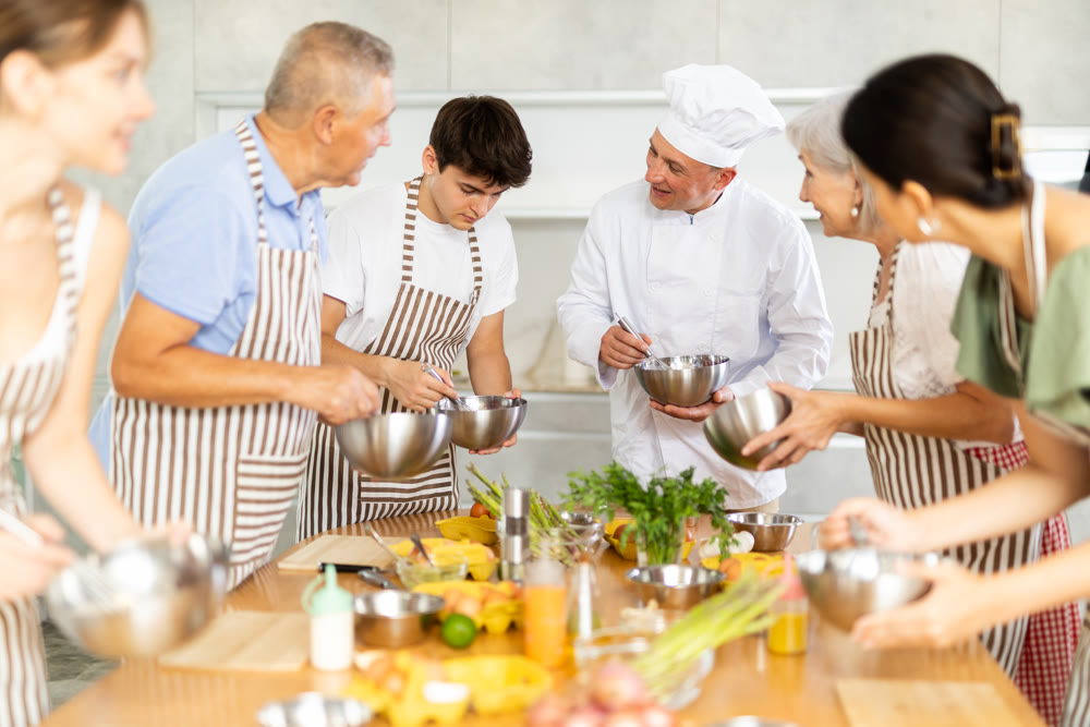 Adult male cook teaches cooking to group of people