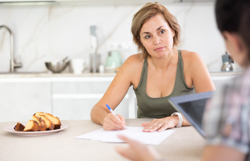 Two middle-aged women having business conversation in the kitchen