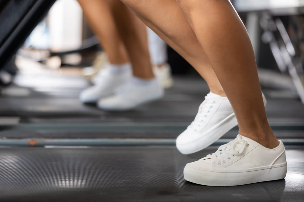 Feet of young girl walk on treadmill in gym