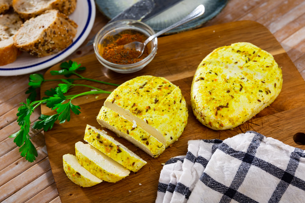 Pieces of hard yellow lithuanian cheese with dried caraway with herbs on the kitchen board