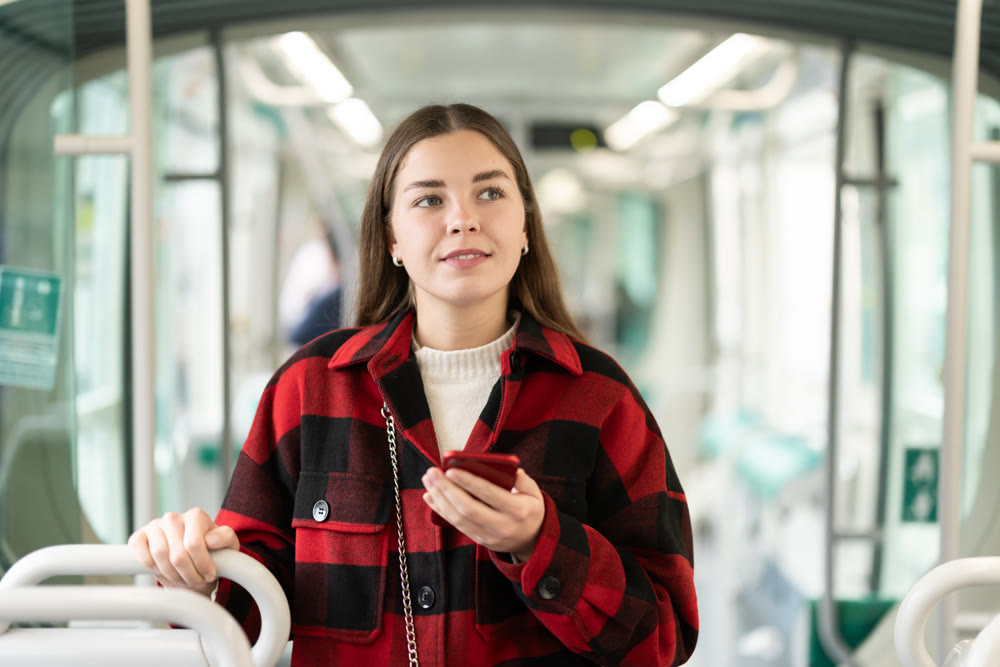 Girl with long hair standing in tram with phone