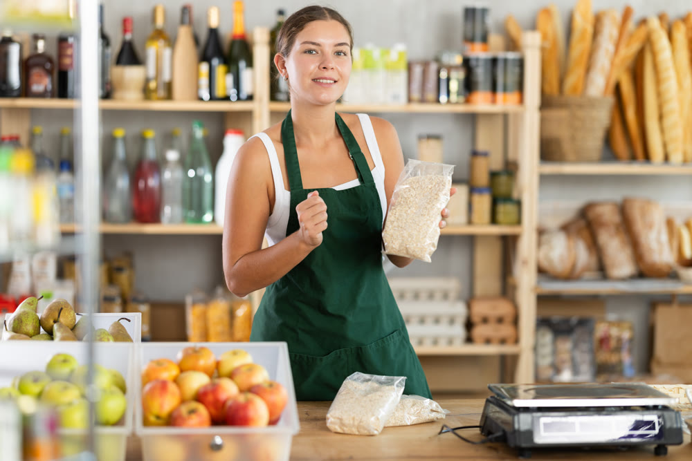 Young woman seller offering oat flakes in grocery store