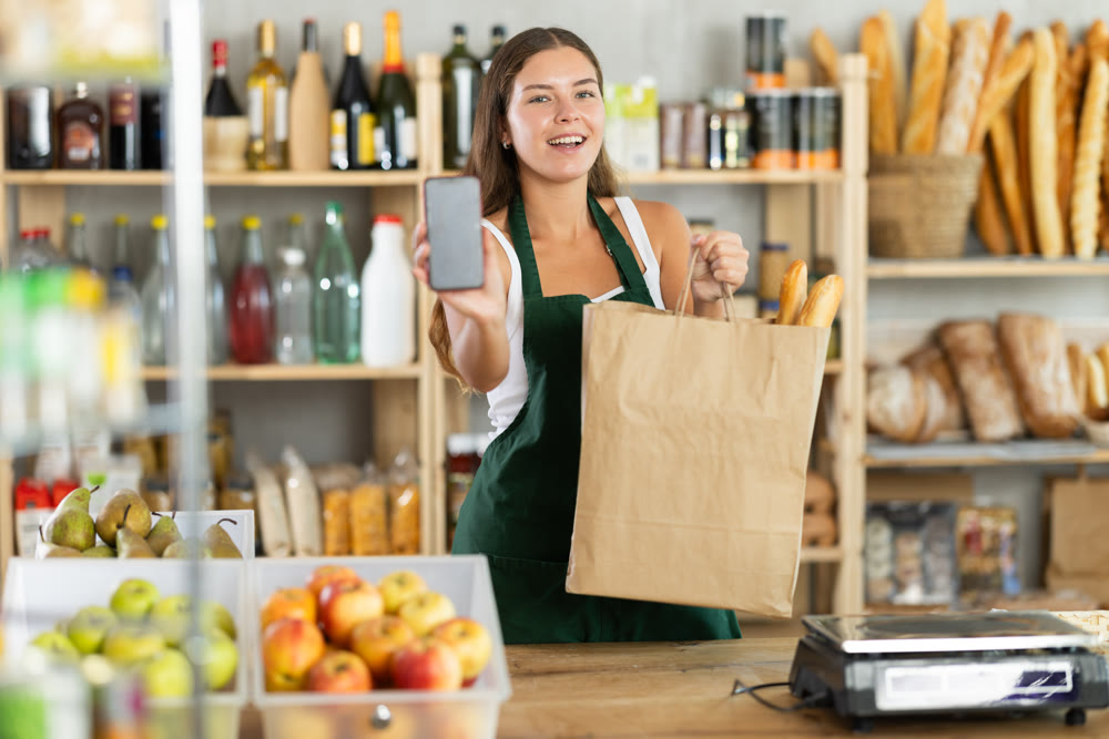 Young woman seller showing information on phone