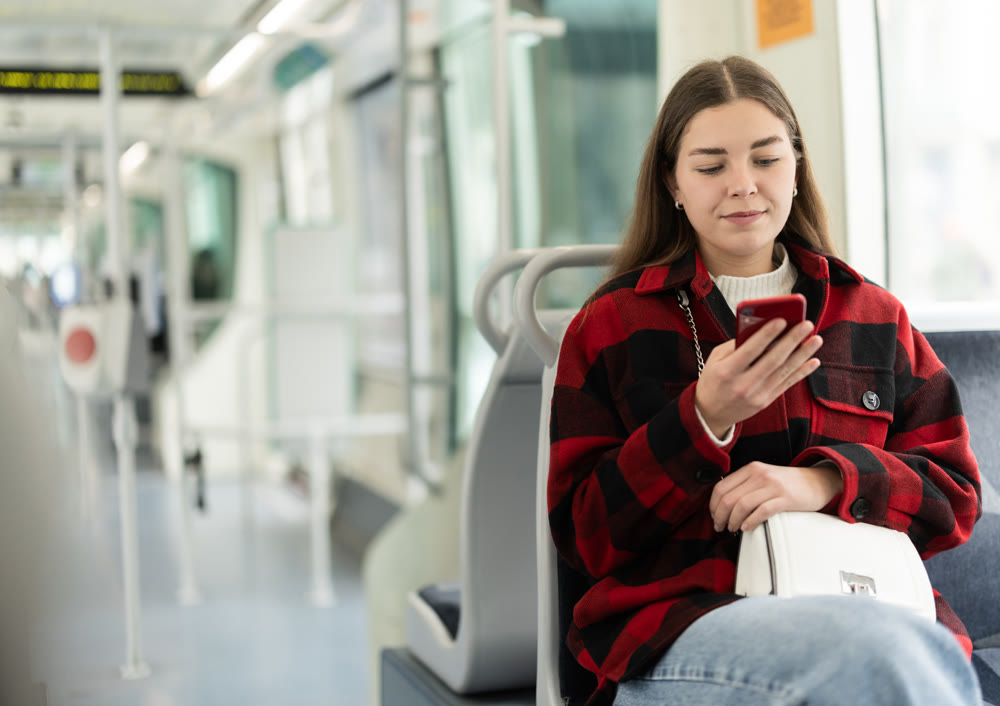 Woman sitting in tram car with phone