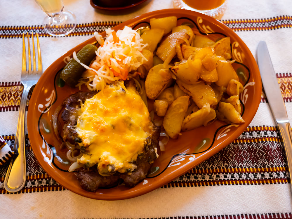 Dish of pork in Poltava with fried potatoes, pickled cabbage and cucumber