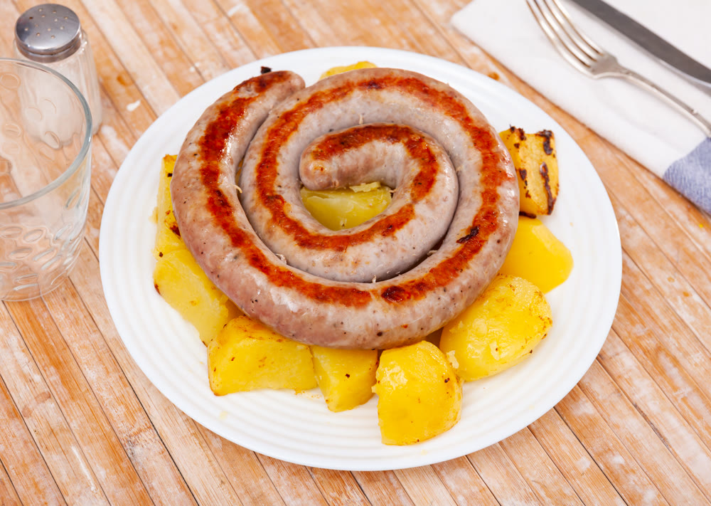 Fried potatoes and treditional spanish pork sausage butifarra on plate