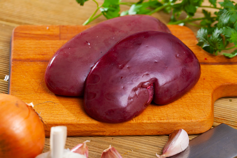 Fresh raw pork kidneys with spices on wooden table